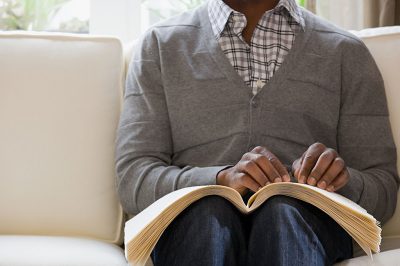 Blind man reading a braille book (Credit: XiXinXing via Shutterstock)