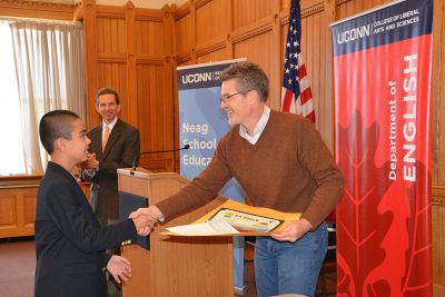 Jason Courtmanche from the UConn Dept. of English and the Connecticut Writing Project, recognizes one of the student honorees. In the background is Doug Kaufman, from the Neag School, who served as another faculty advisor.