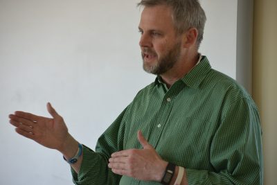 Professor Todd Campbell gives a lecture to graduate students. He's wearing a green shirt.