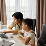 Parent and child using laptop together.