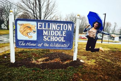 Enrique jumping up alongside the Ellington Middle School sign.