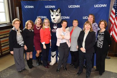 Group of women in front of UConn banner.