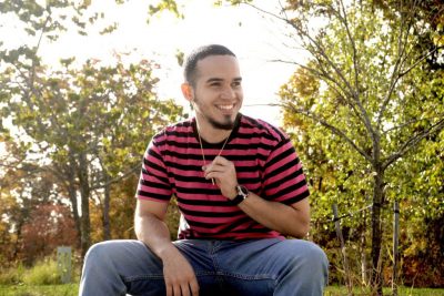 Class of 2021 senior Amable Enrique Aristy Cabrera ’21 (ED) sitting outdoors and smiling off-camera.