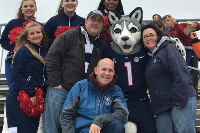 Jonathan the mascot surrounded by fans and cheerleaders