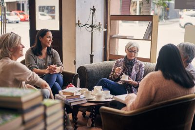 Women sitting at coffee shop discussing a book.