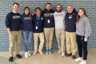 Group of individuals wearing UConn shirts gather.