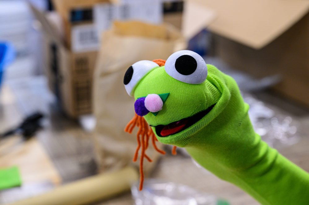 Green sock puppet with googly eyes.