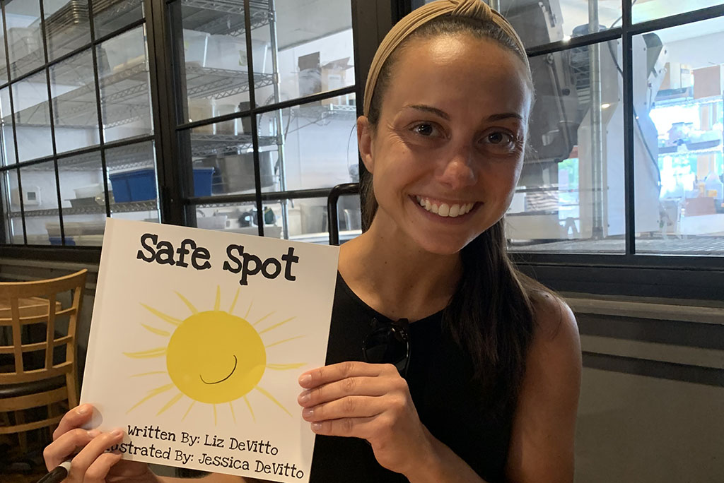 Smiling female holds book "Safe Spot"