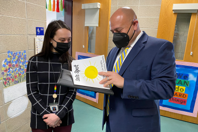 Female teacher and male administrator look at a book.