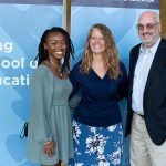 Three adults standing in front of a Neag School banner.