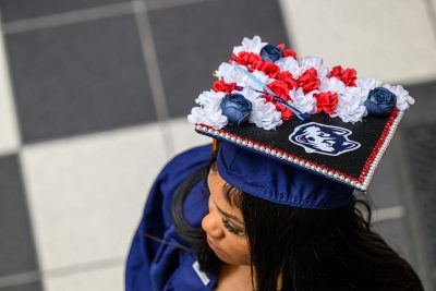 Photo of decorated graduation cap and student. [links to education.uconn.edu/commencement]