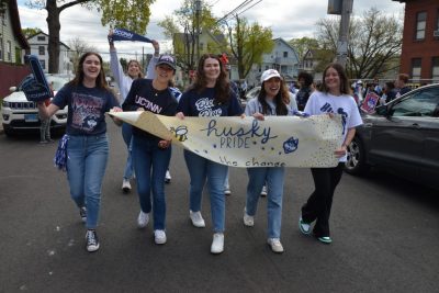 Female students walk with banner during Kennelly School's UConn Day.